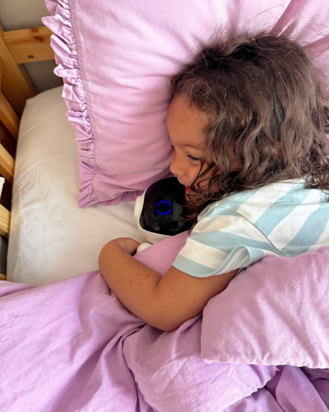 A child lying down with Otto tucked in beside her, smiling at it