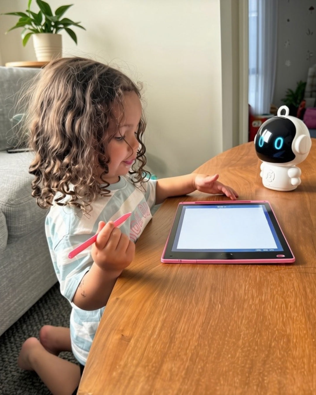A child drawing at a table with Otto sitting beside her, eyes lit